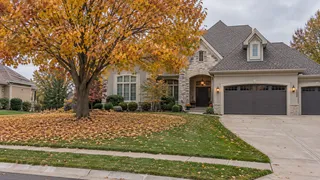 Lenexa, KS home with golden fall leaves blanketing the front lawn under a large maple tree