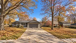 Prairie Village, KS ranch home on a tree-lined street with fall leaves covering the lawn and curb